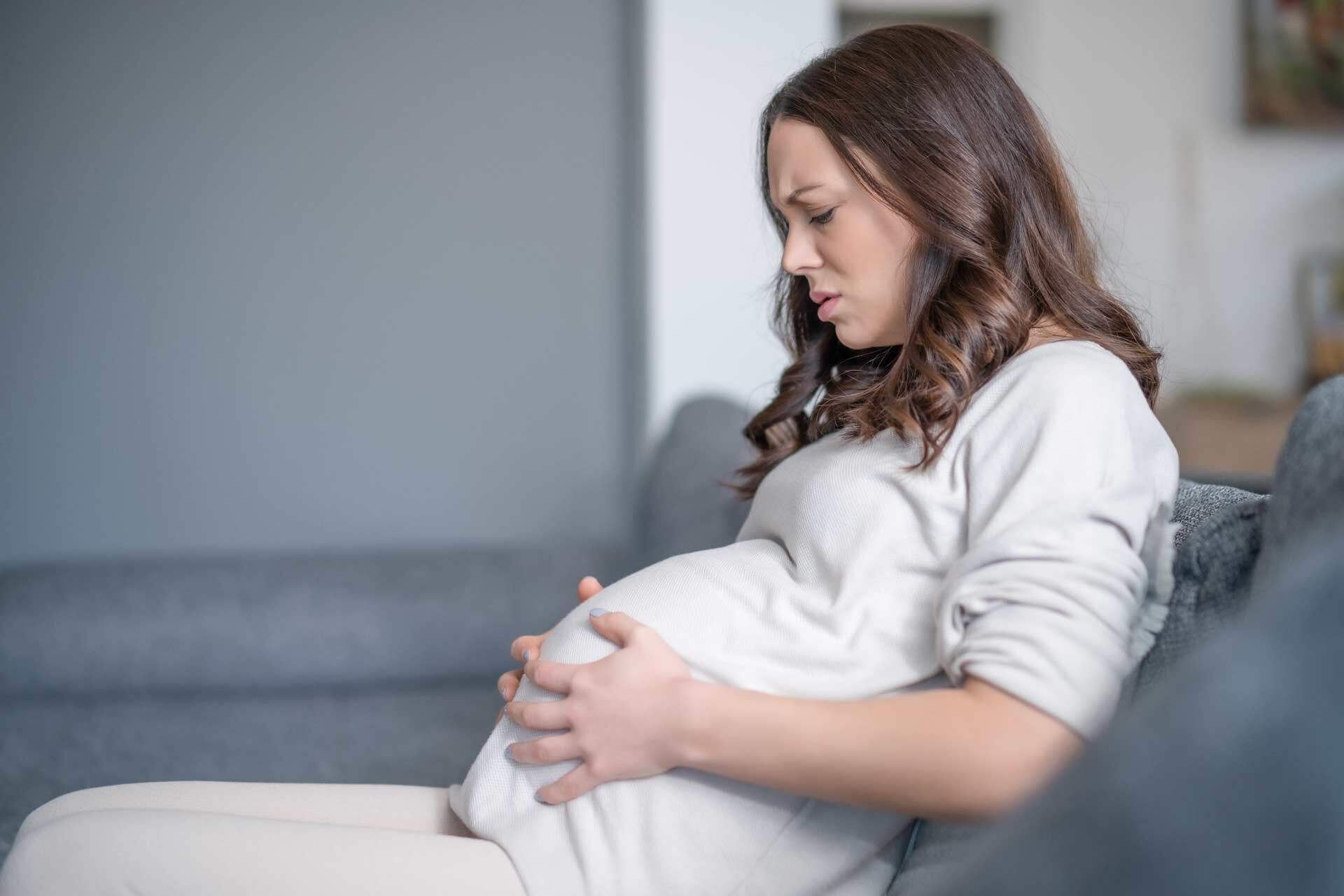 Bild zeigt eine schwangere Frau, wie sie sich ihnen Babybauch angestrengt hält.