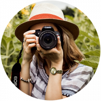 Partner Fotograf, Fotografin guckt durch Canon EOS auf den Betrachter der Webseite.