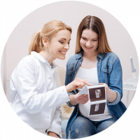 Partner Frauenärzte, Frauenärztin zeigt einer Patientin stolz ein Ultraschallbild.