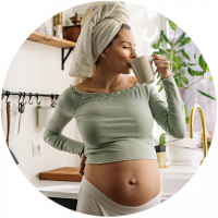 Partner Mama Influencer, Schwangere trinkt ihren Kaffee mit einem Handtuch vom Duschen auf dem Kopf.